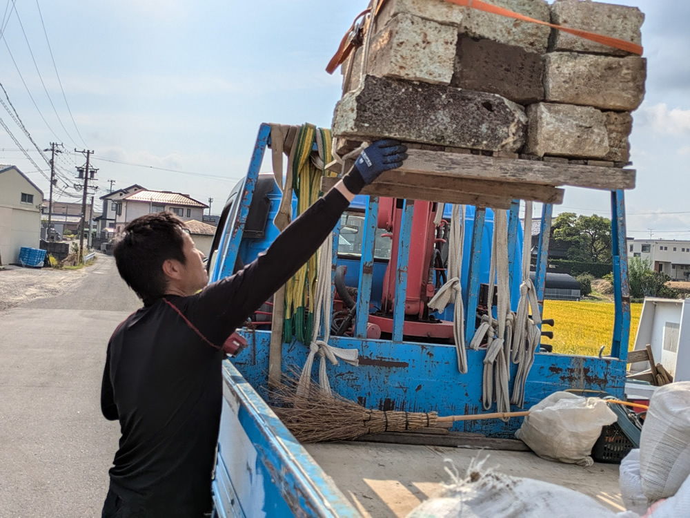 クレーンで墓じまいの墓石を持ち上げて作業をしている筒木社長の写真