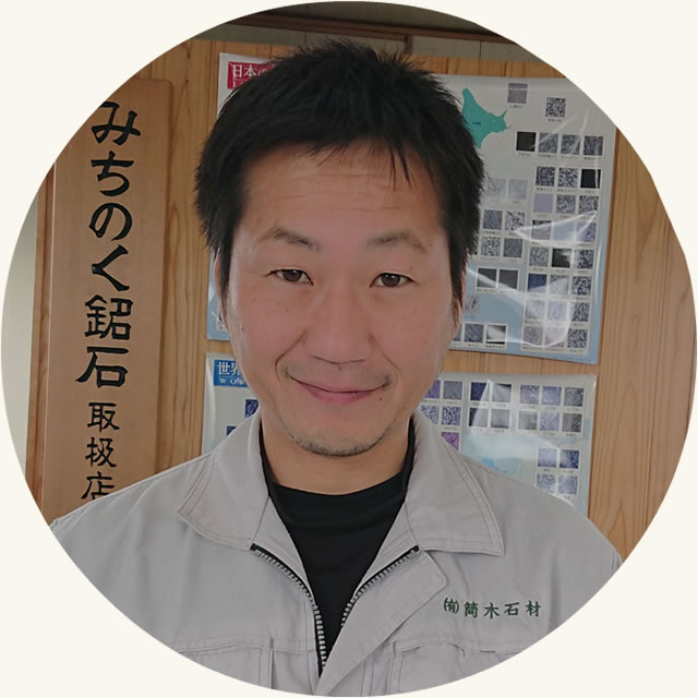 作業服姿の筒木社長が正面を向いて座っている写真