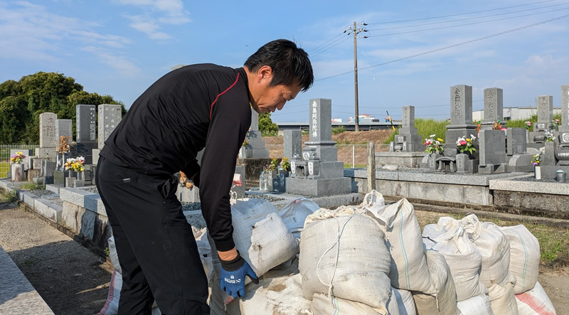土能袋に入れらた墓石を運ぶ筒木社長
